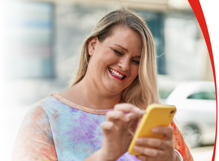 Overweight woman on street smiling navigating her phone