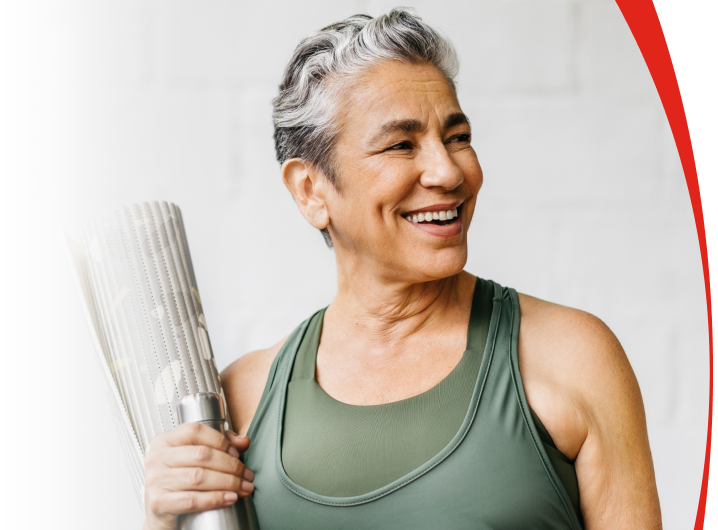 Older woman carrying yoga mat looking away 