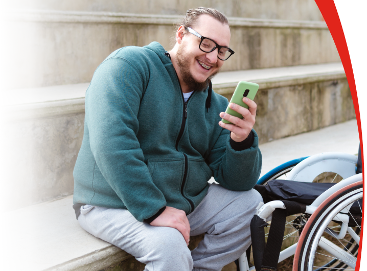 Man sitting on steps looking at phone next to his wheelchair